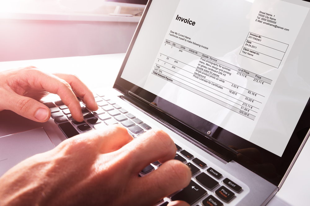 Close-up Of Businessman's Hands Working On Invoice