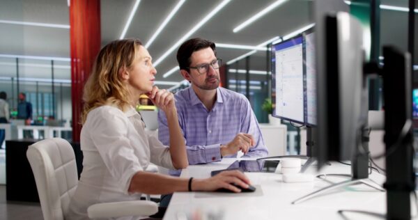 Professional Accountants Preparing Tax Invoices On Office Desktop Computers
